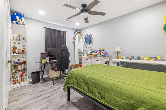a bedroom with a bed a desk and chair with wooden floor