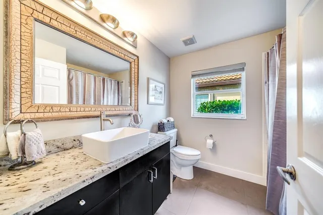 a bathroom with a granite countertop sink toilet and mirror