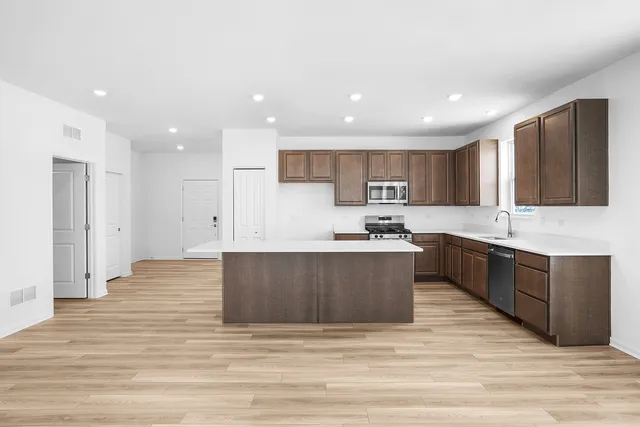 a large kitchen with stainless steel appliances granite countertop a large counter top a sink and a stove