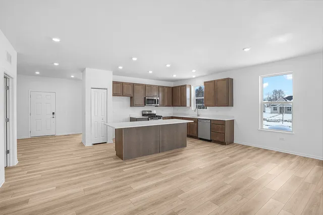 a large kitchen with kitchen island a sink wooden floor and stainless steel appliances