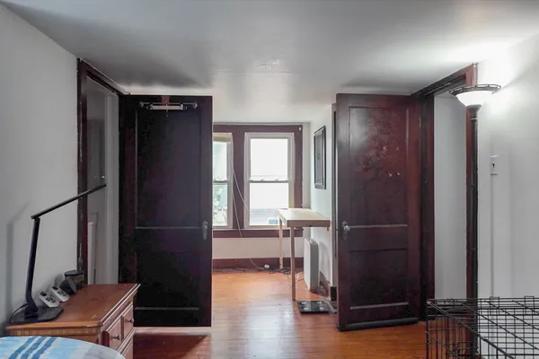 an empty room with wooden floor windows and entryway