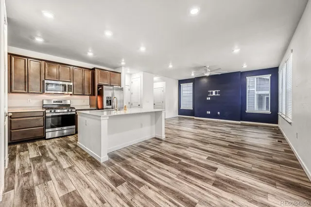 a large white kitchen with kitchen island a sink dishwasher a stove and a refrigerator with wooden floor