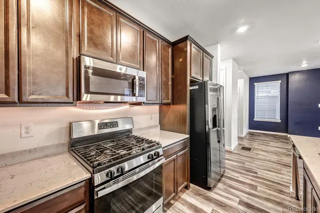 a kitchen with stainless steel appliances granite countertop a stove refrigerator and microwave