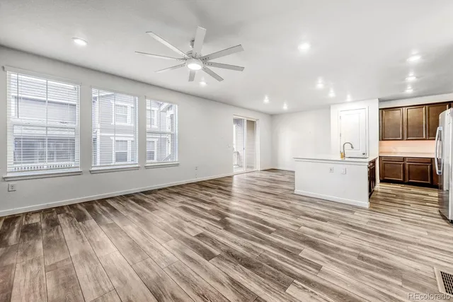 a view of an empty room with a window and kitchen view