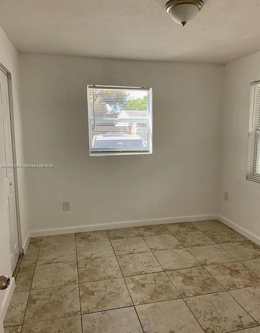 1277 Northwest 58th Street Miami, FL 33142 - Photo 2 of 9 an empty room with white walls and tiles