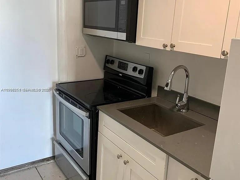 1277 Northwest 58th Street Miami, FL 33142 - Photo 6 of 9 a close view of a sink and dishwasher in kitchen with stainless steel appliances