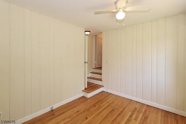 an empty room with wooden floor closet and windows