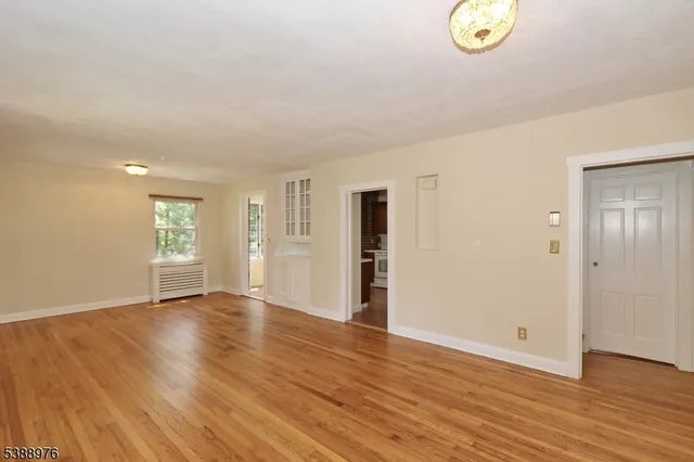 an empty room with wooden floor and window