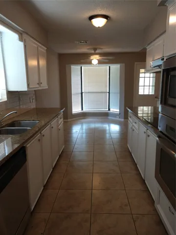 a kitchen with granite countertop a stove a sink and a refrigerator