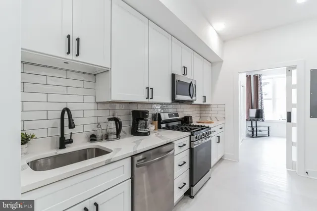 a kitchen with stainless steel appliances granite countertop white cabinets a sink a stove a refrigerator and white cabinets