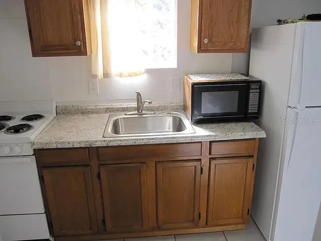 a kitchen with granite countertop a sink stove and microwave