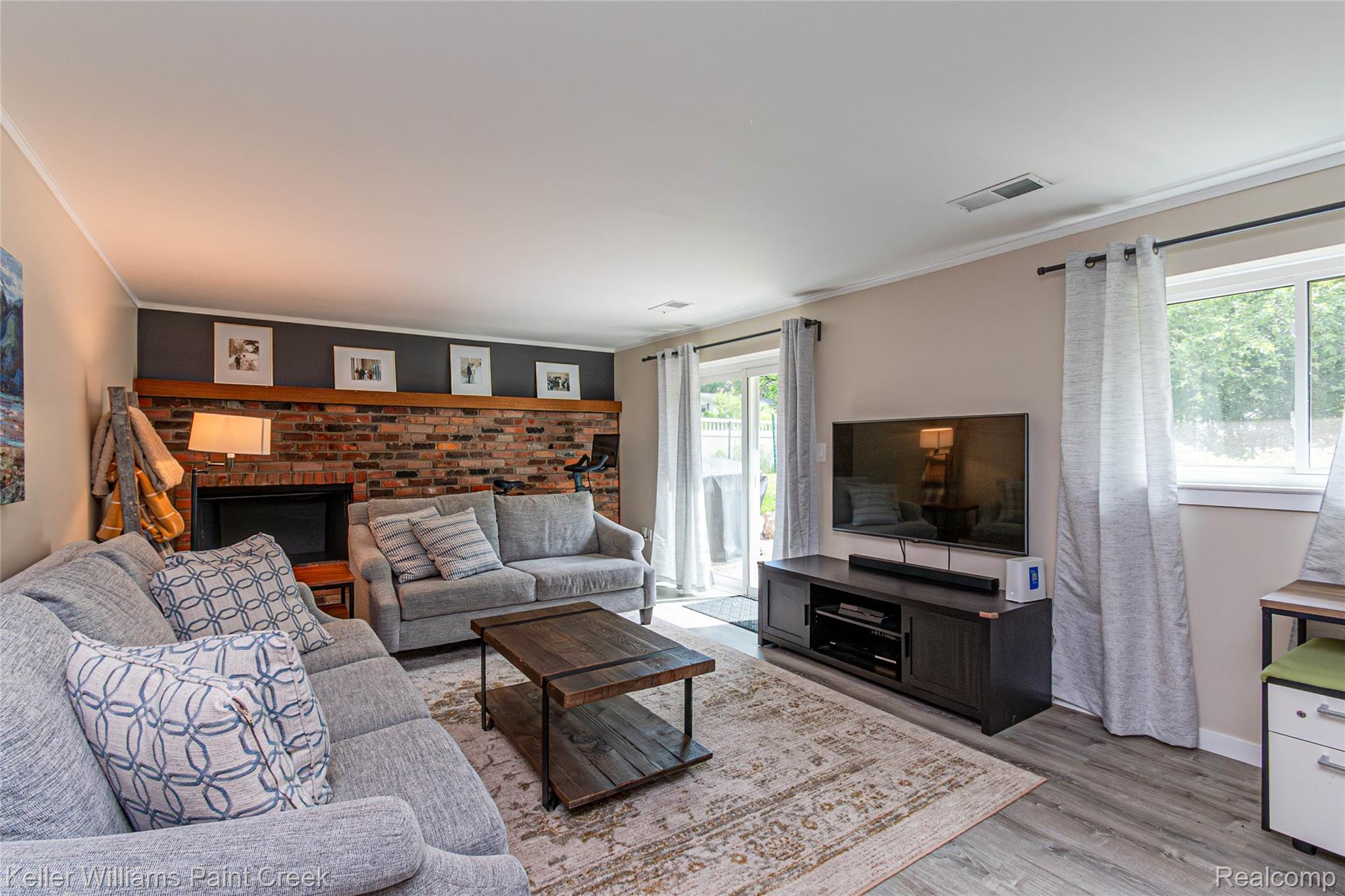 7093 Stonebrook Road West Bloomfield, MI 48322 - Photo 45 of 64 Spacious living area featuring a brick fireplace, wood-finish flooring, a glass sliding door, and a large window