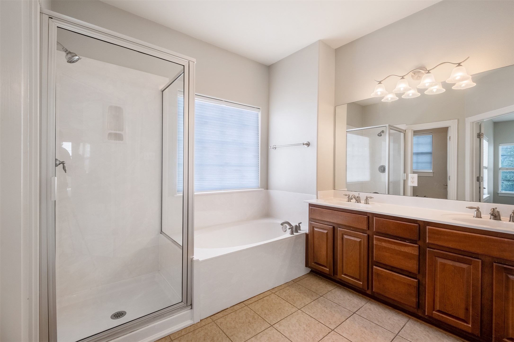 6715 Windrift Way, Unit 8 Austin, TX 78745 - Photo 15 of 24 A well-appointed bathroom features a glass-enclosed shower, deep soaking tub, and a long vanity with dual sinks.