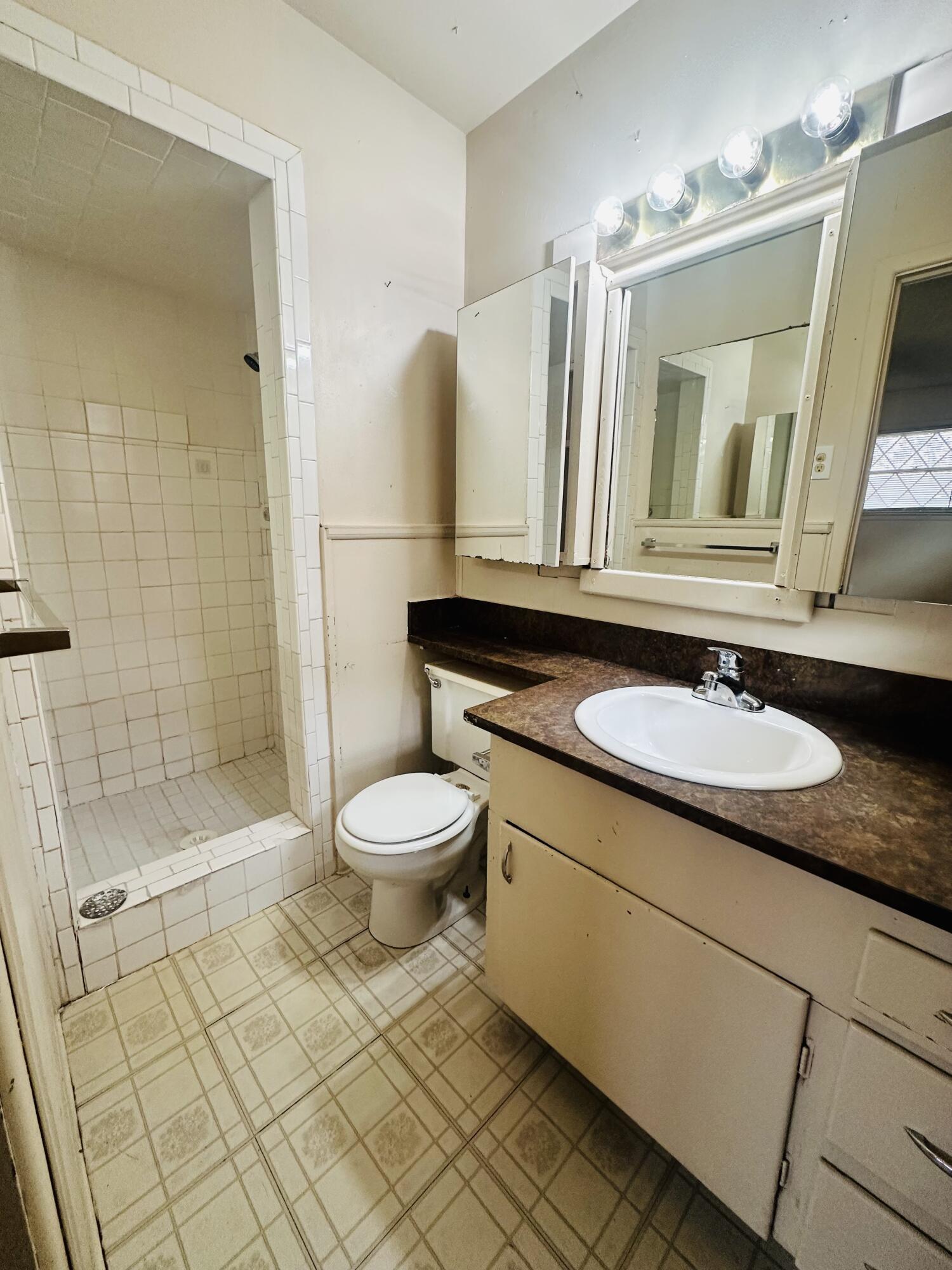 4918 14th Street Lubbock, TX 79416 - Photo 26 of 38 a bathroom with a granite countertop sink toilet a mirror and shower