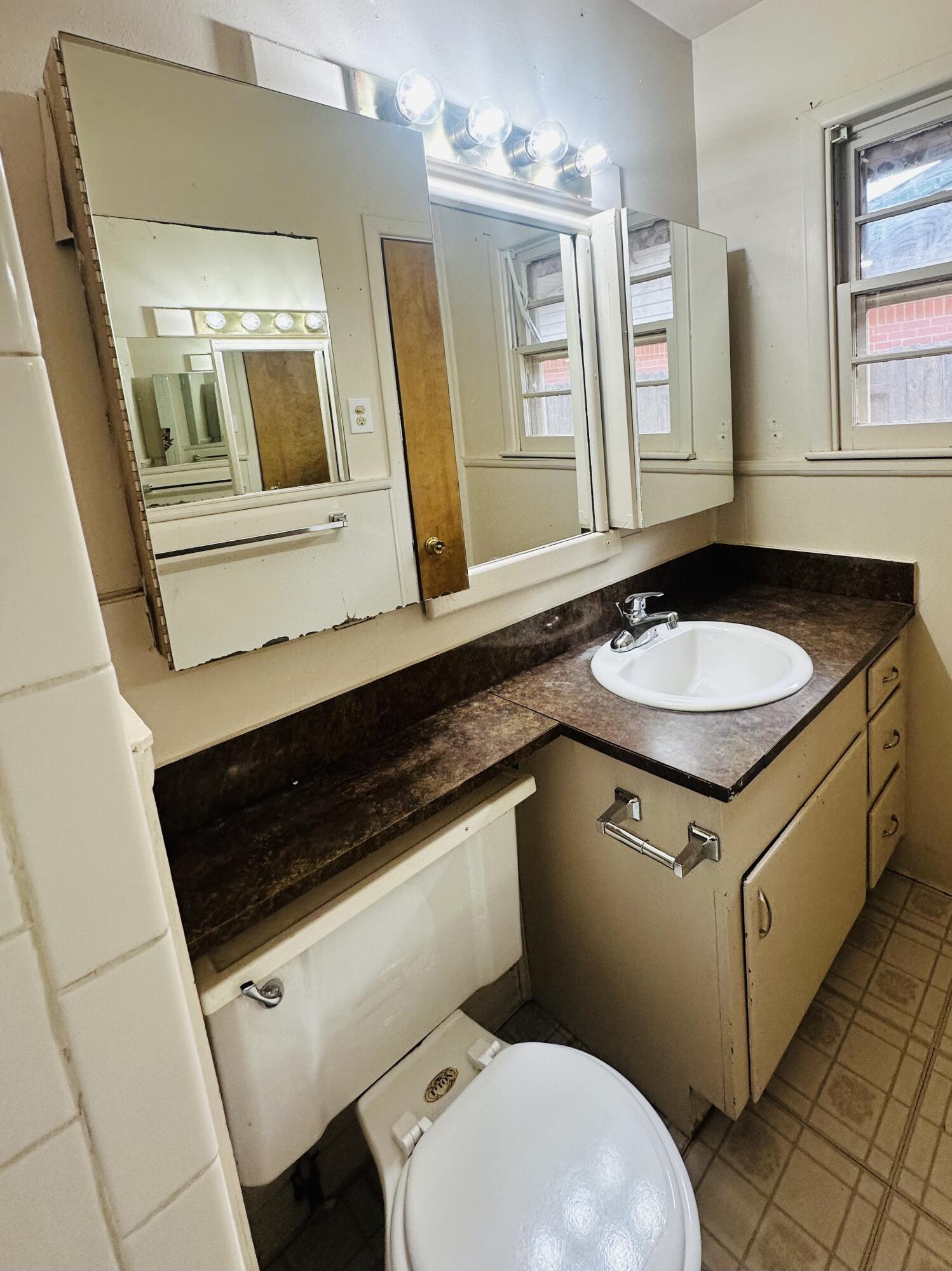 4918 14th Street Lubbock, TX 79416 - Photo 27 of 38 a bathroom with a granite countertop toilet sink and mirror