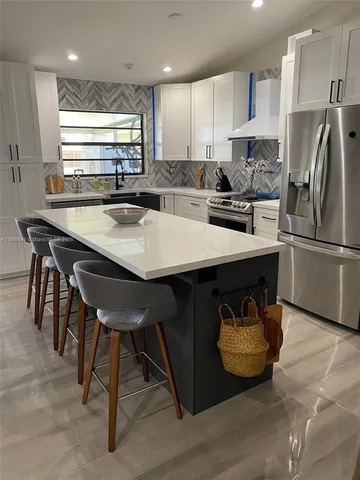 a kitchen with stainless steel appliances granite countertop a sink a stove a refrigerator and island