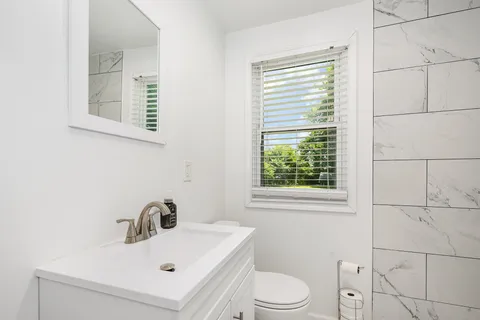 a bathroom with a sink a toilet and a window