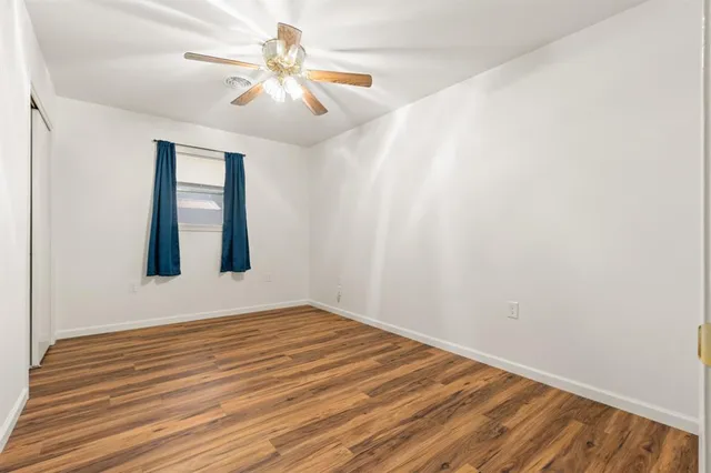 a view of an empty room with window and wooden floor
