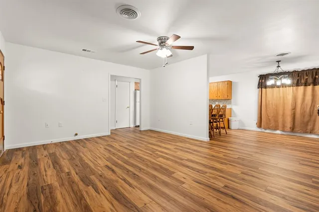 a view of an empty room with a window and wooden floor