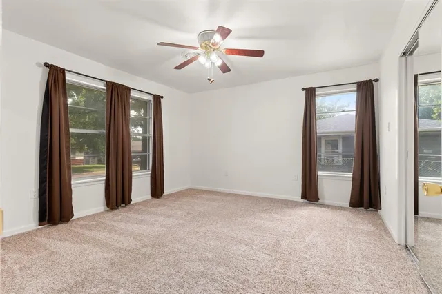 a view of an empty room with chandelier fan and a window