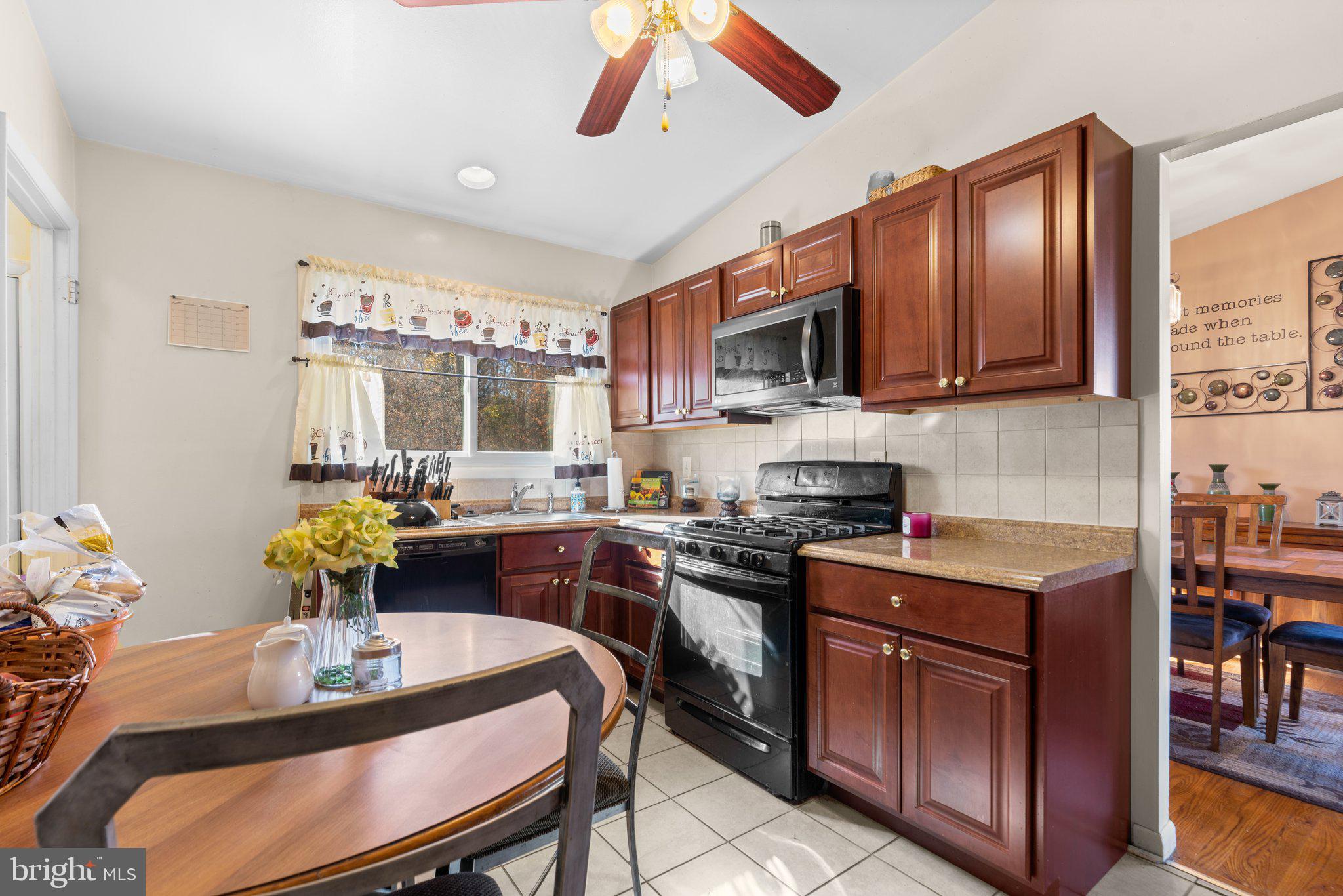 4727 Byron Road Windsor Mill, MD 21244 - Photo 14 of 35 a kitchen with stainless steel appliances granite countertop a stove refrigerator a dining table and chairs with wooden floor