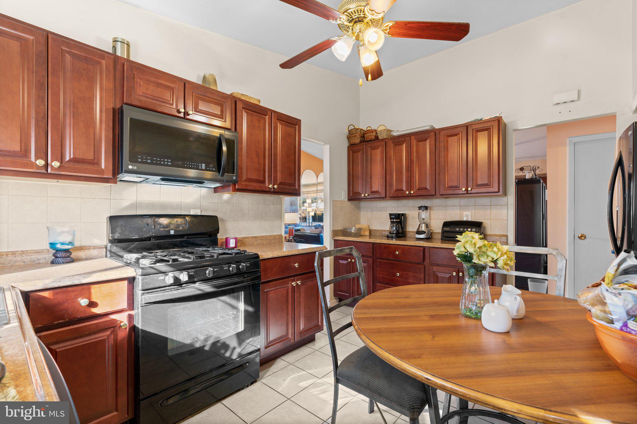 4727 Byron Road Windsor Mill, MD 21244 - Photo 16 of 35 a kitchen with stainless steel appliances granite countertop a stove top oven a refrigerator a sink with a dining table and chairs