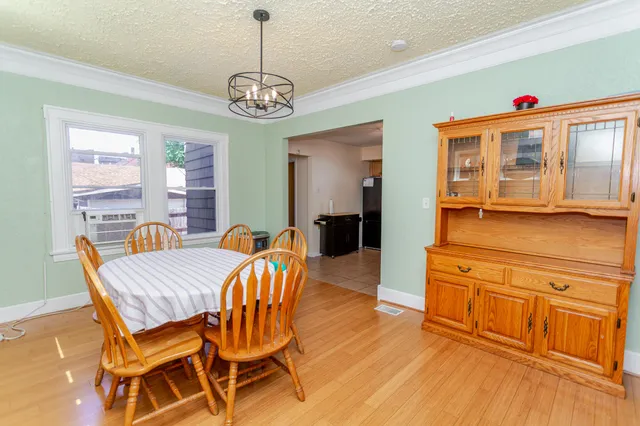 a dining room with wooden floor a chandelier a wooden table and chairs