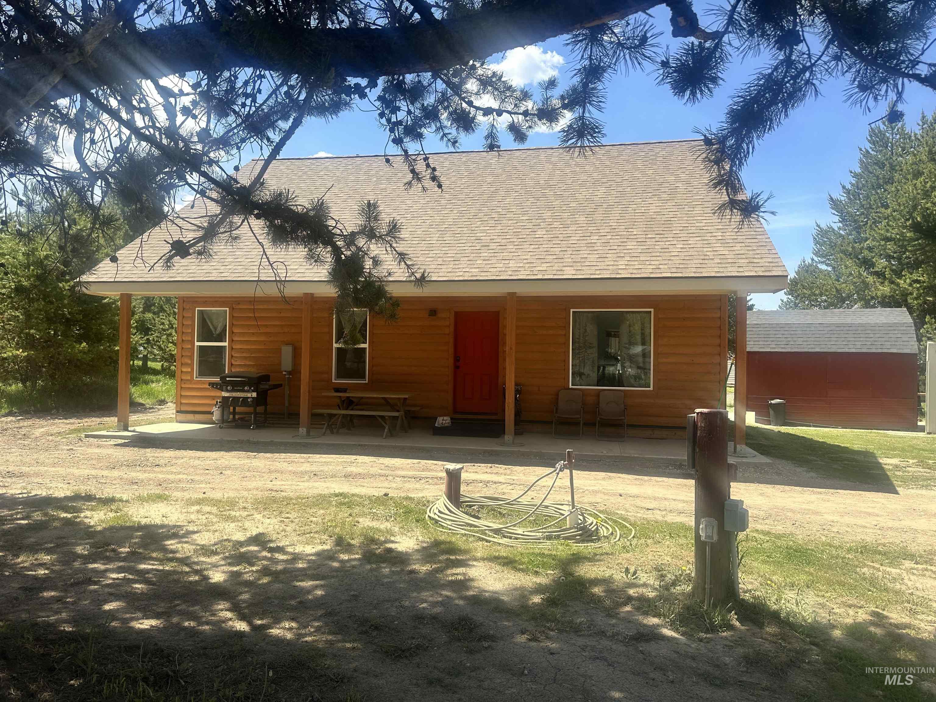22 West Prospectors Drive Cascade, ID 83611 - Photo 2 of 29 Wood-sided exterior featuring a covered front porch and a red entrance door