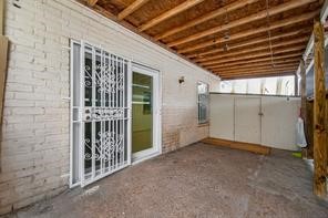6201 Ranchester Drive, Unit 29 Houston, TX 77036 - Photo 17 of 23 Charming covered patio area with secure white metal door, exposed wood beams, and ample space for outdoor relaxation.