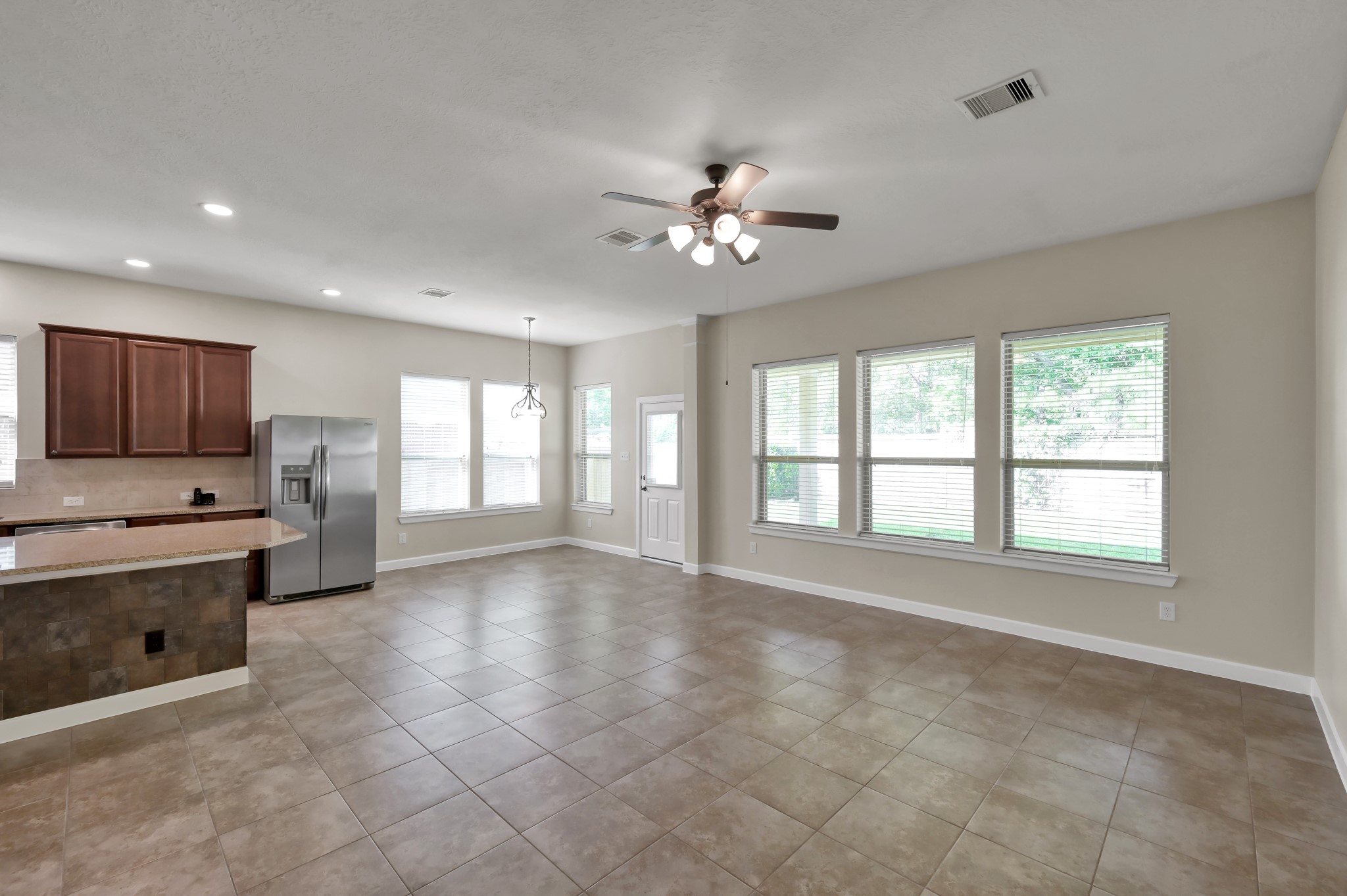 31507 Boulder Cliff Lane Spring, TX 77386 - Photo 13 of 45 This open-concept space features a spacious kitchen with stainless steel appliances and a breakfast bar, flowing into a bright living area with large windows and neutral tile flooring, perfect for entertaining.