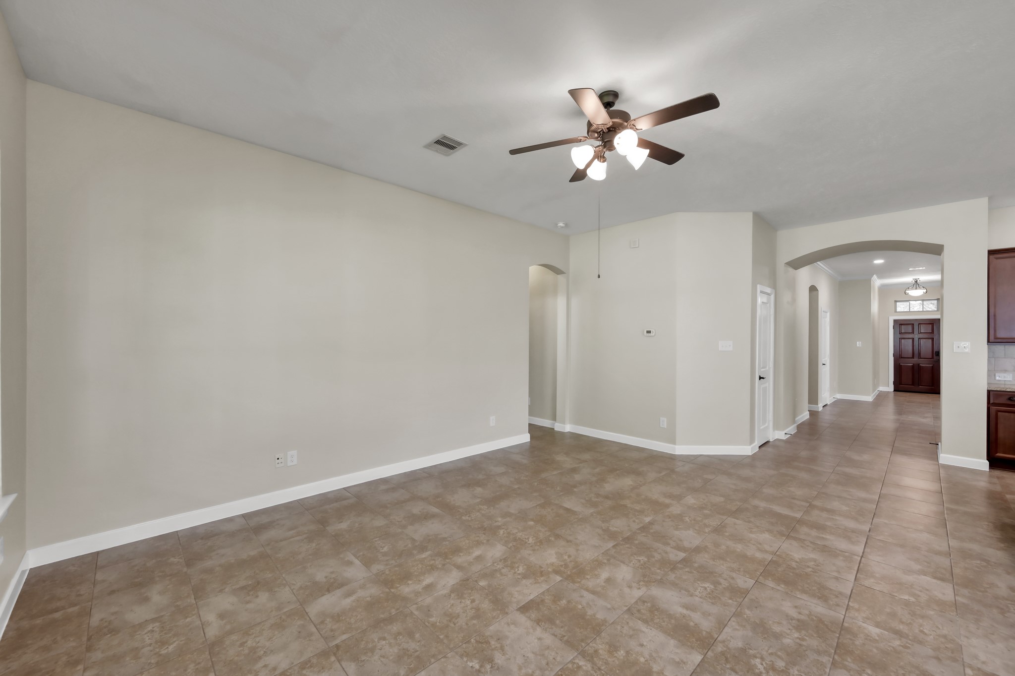 31507 Boulder Cliff Lane Spring, TX 77386 - Photo 15 of 45 This spacious room features neutral-colored walls and tile flooring, complemented by a ceiling fan. An arched hallway leads to additional areas of the home, offering an inviting and open layout.