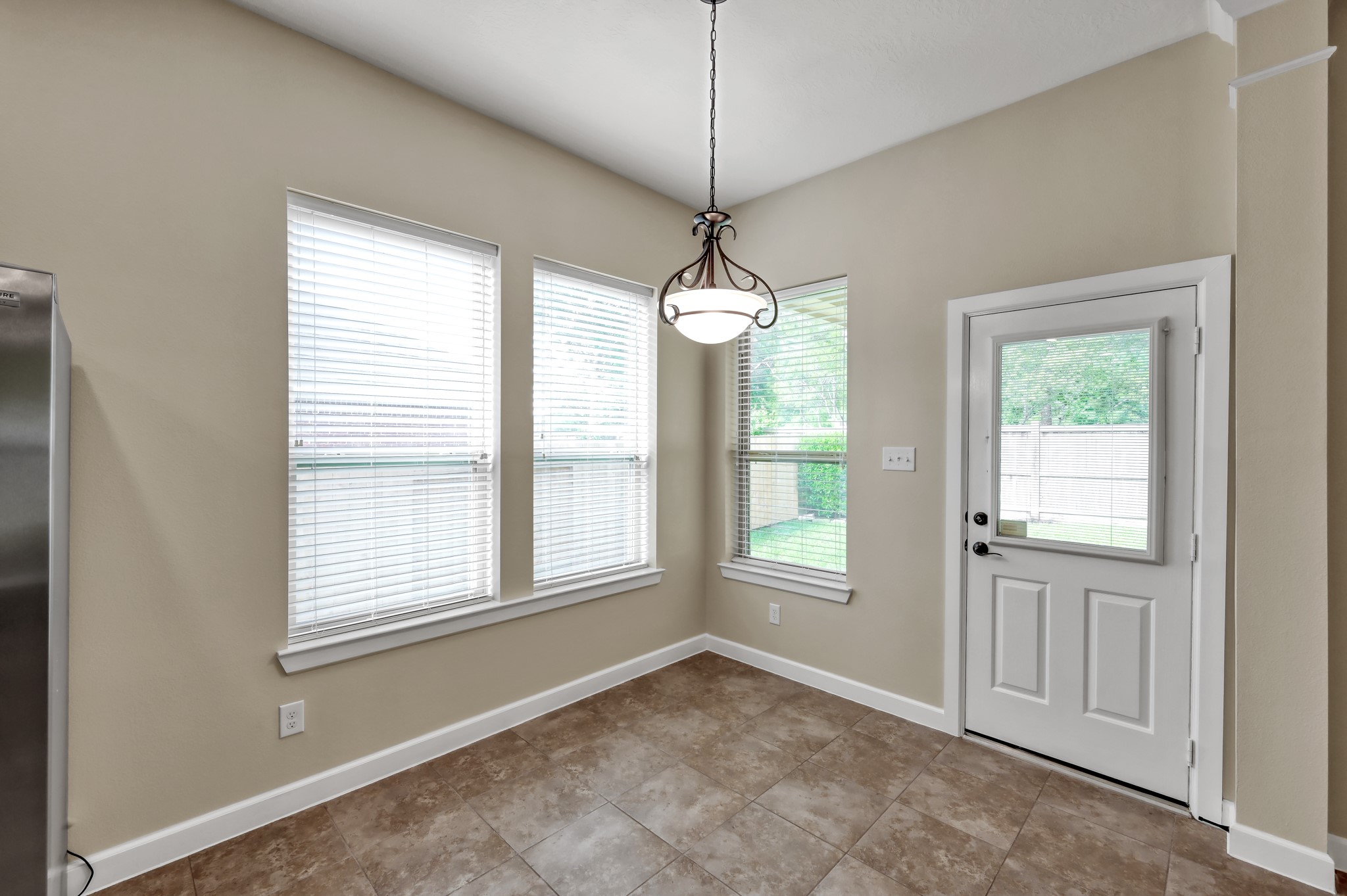 31507 Boulder Cliff Lane Spring, TX 77386 - Photo 20 of 45 Bright and inviting breakfast nook with large windows, tile flooring, and a stylish hanging light fixture. The space includes a door leading to the backyard, offering easy outdoor access.