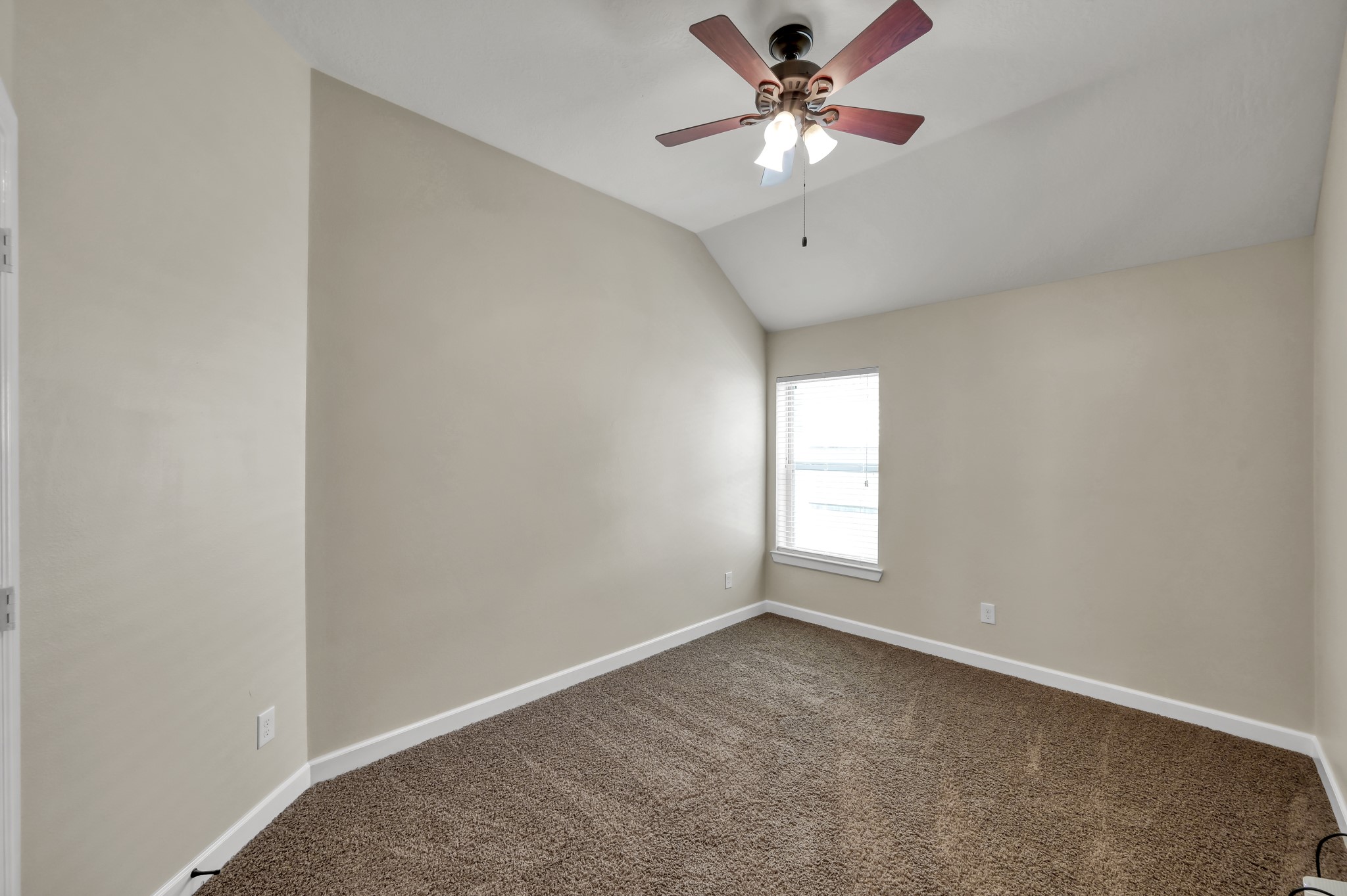 31507 Boulder Cliff Lane Spring, TX 77386 - Photo 28 of 45 This room features neutral walls, a vaulted ceiling, and a ceiling fan with lights. It has soft carpeting and a window providing natural light, creating a cozy and inviting space.