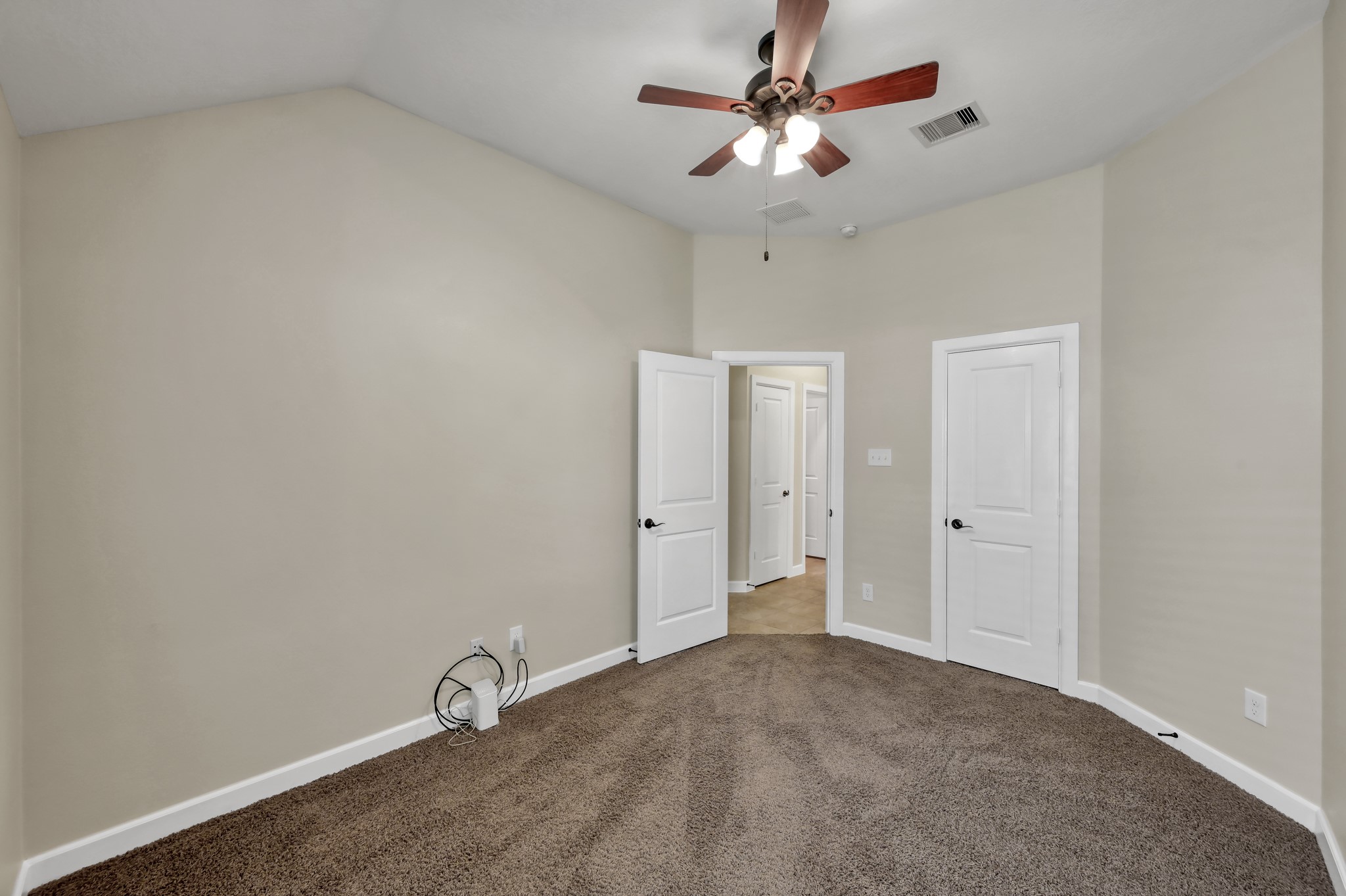 31507 Boulder Cliff Lane Spring, TX 77386 - Photo 29 of 45 This room features neutral walls, a ceiling fan with lights, and carpeted flooring. It includes two white doors and has a spacious feel, ideal for a bedroom or office.