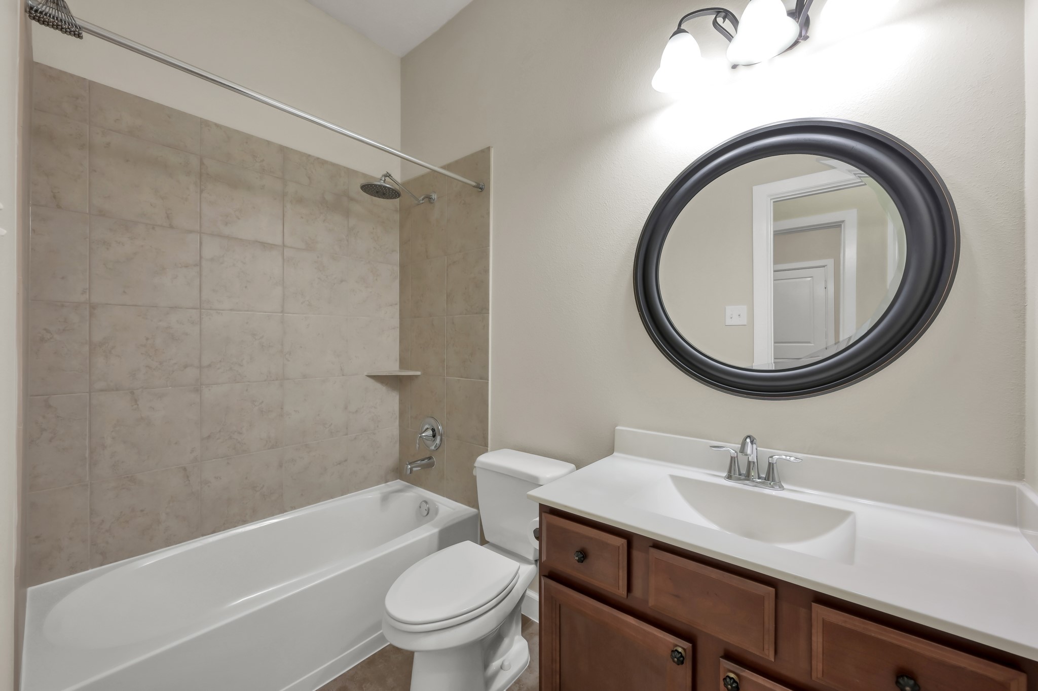 31507 Boulder Cliff Lane Spring, TX 77386 - Photo 30 of 45 This bathroom features a clean, modern design with a tiled shower and bathtub, a sleek vanity with a dark wood cabinet, and an elegant oval mirror. The neutral color palette and ample lighting create a bright and inviting space.