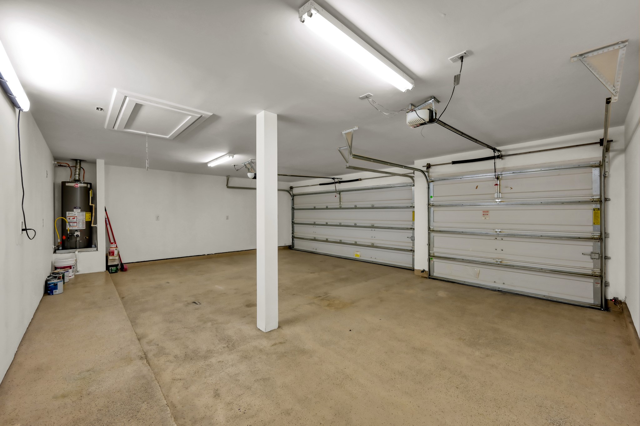 31507 Boulder Cliff Lane Spring, TX 77386 - Photo 34 of 45 This spacious two-car garage features clean, white walls and a concrete floor. It includes two large garage doors, overhead lighting, and a water heater in the corner, offering ample storage and functionality.