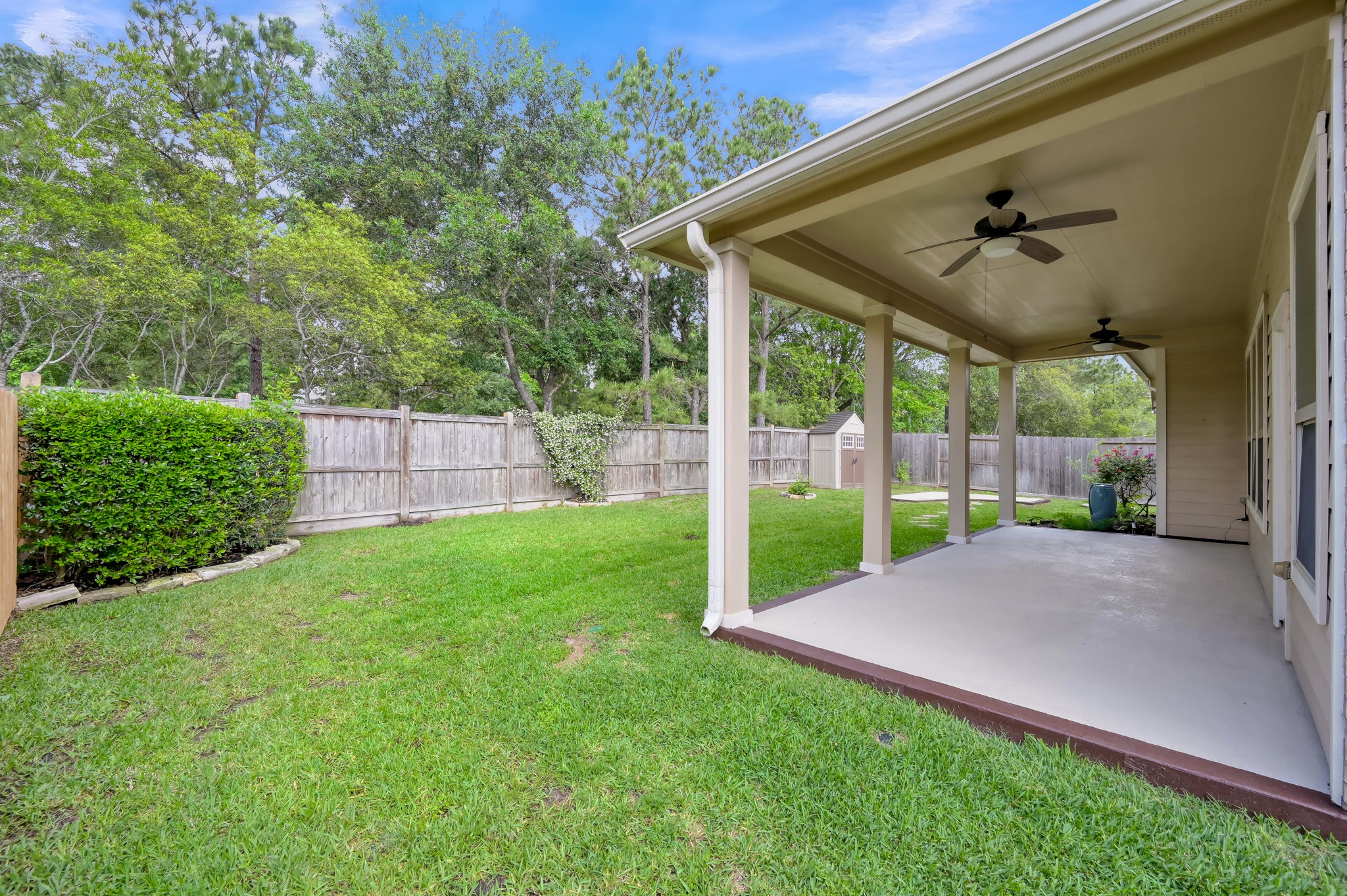 31507 Boulder Cliff Lane Spring, TX 77386 - Photo 35 of 45 This photo showcases a spacious backyard with a covered patio, ceiling fans, and a well-maintained lawn, perfect for outdoor relaxation and entertainment.