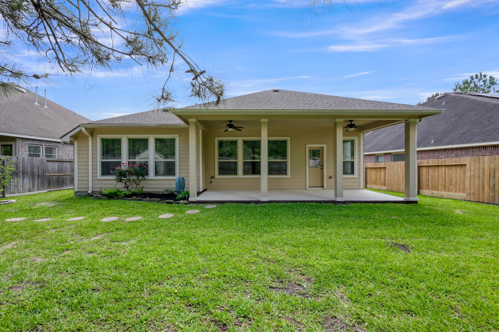 31507 Boulder Cliff Lane Spring, TX 77386 - Photo 36 of 45 This photo showcases a charming backyard with a covered patio, ideal for outdoor relaxation. The space features a well-maintained lawn, bordered by a wooden fence for privacy, and a few plants adding a touch of greenery.