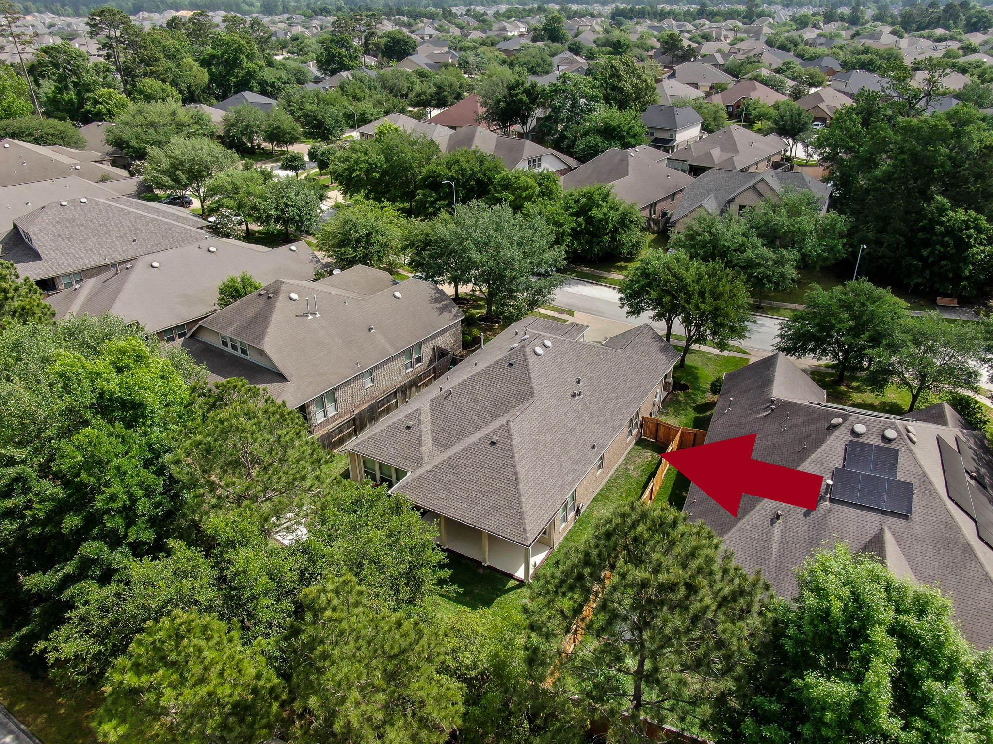 31507 Boulder Cliff Lane Spring, TX 77386 - Photo 40 of 45 This aerial photo showcases a suburban neighborhood with well-maintained houses surrounded by lush greenery. The property highlighted by a red arrow features a spacious yard, offering privacy and a peaceful setting.