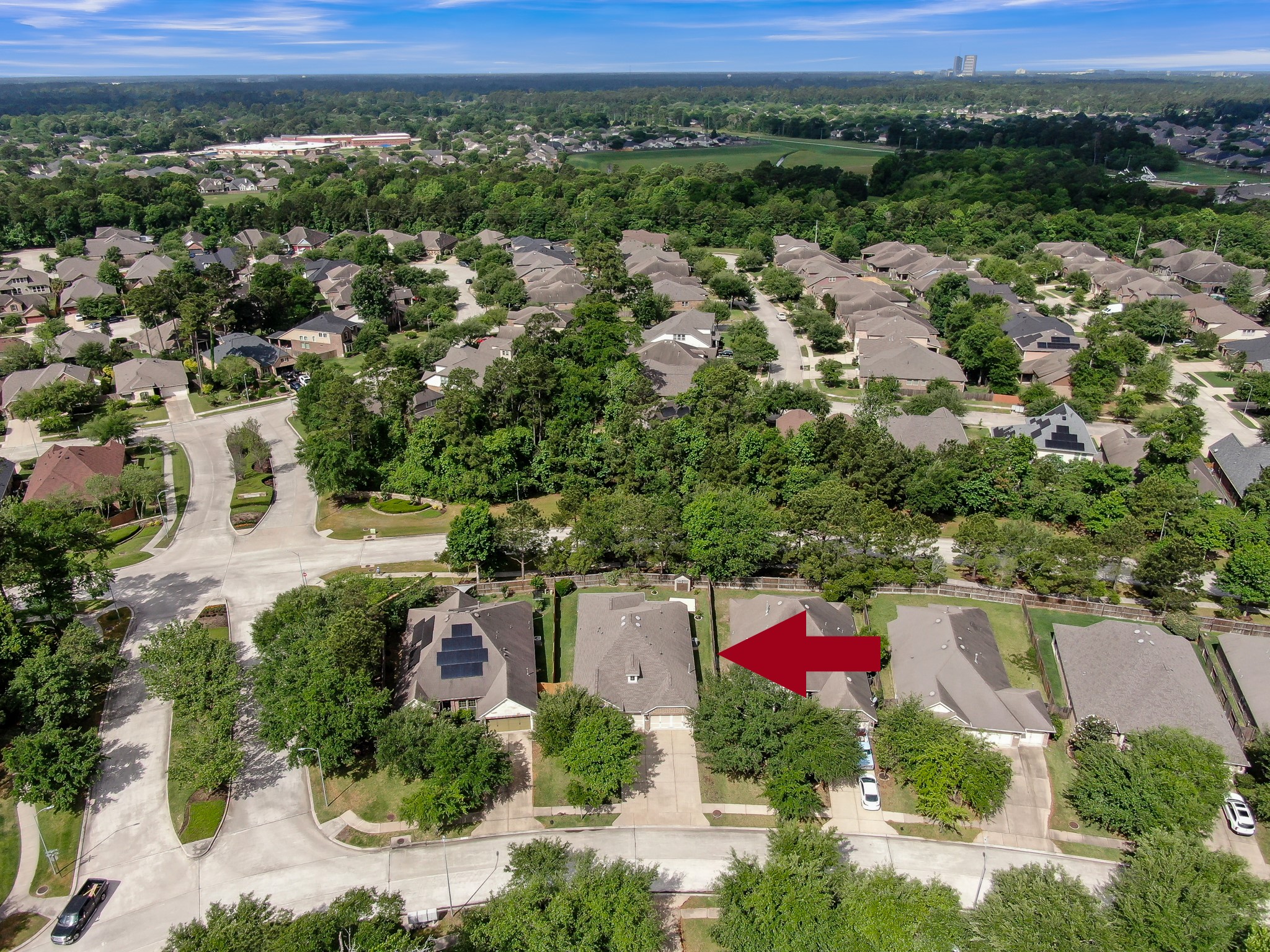 31507 Boulder Cliff Lane Spring, TX 77386 - Photo 42 of 45 This aerial photo showcases a suburban neighborhood with well-maintained homes surrounded by lush greenery. The area appears peaceful and family-friendly, with tree-lined streets and ample spacing between houses. A red arrow highlights a specific home, suggesting it may be for sale.