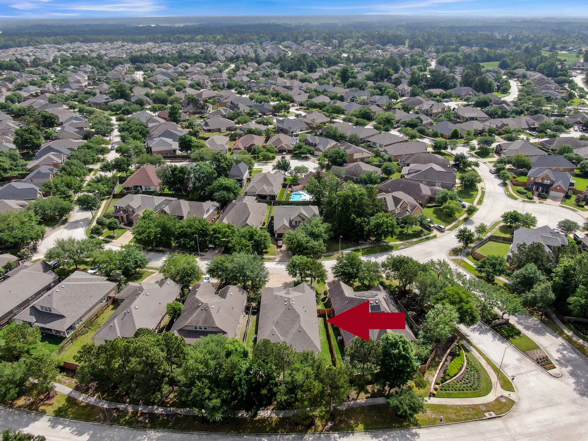 31507 Boulder Cliff Lane Spring, TX 77386 - Photo 43 of 45 This aerial photo showcases a suburban neighborhood with tree-lined streets and well-maintained homes. The red arrow points to a specific house, situated in a quiet, residential area with nearby green spaces.