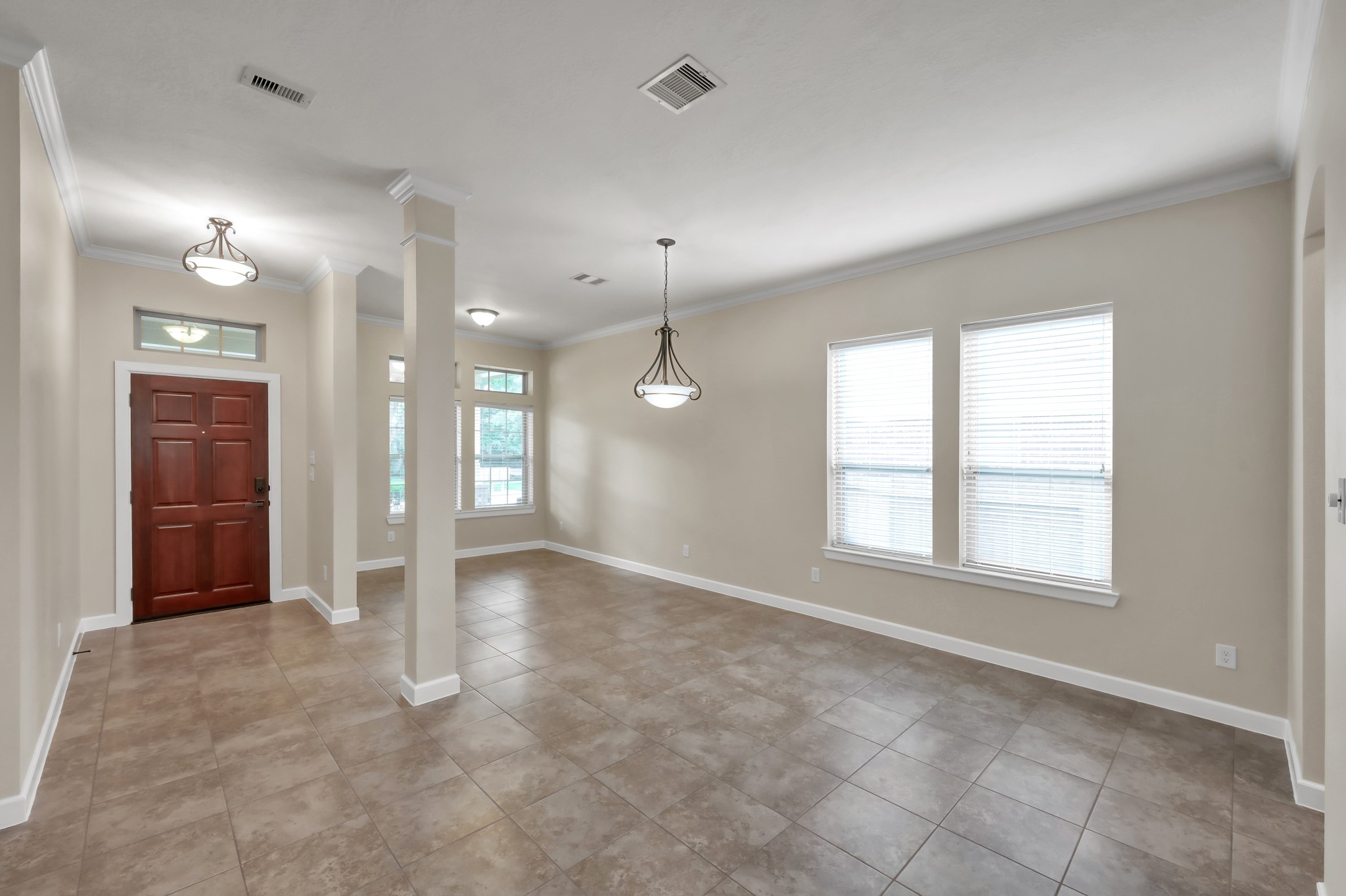 31507 Boulder Cliff Lane Spring, TX 77386 - Photo 8 of 45 This photo showcases a bright, open entryway and living area with neutral walls, tiled flooring, and large windows for natural light. The space features modern light fixtures and a wooden front door, creating a welcoming atmosphere.