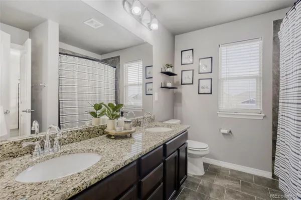 a bathroom with a granite countertop sink a toilet and mirror