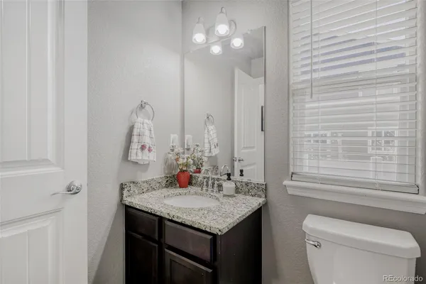 a bathroom with a granite countertop sink a toilet and a mirror