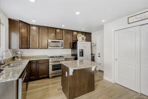 a large kitchen with stainless steel appliances granite countertop a sink stove and refrigerator