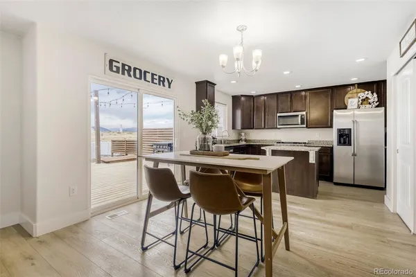 a kitchen with stainless steel appliances a dining table chairs refrigerator and cabinets