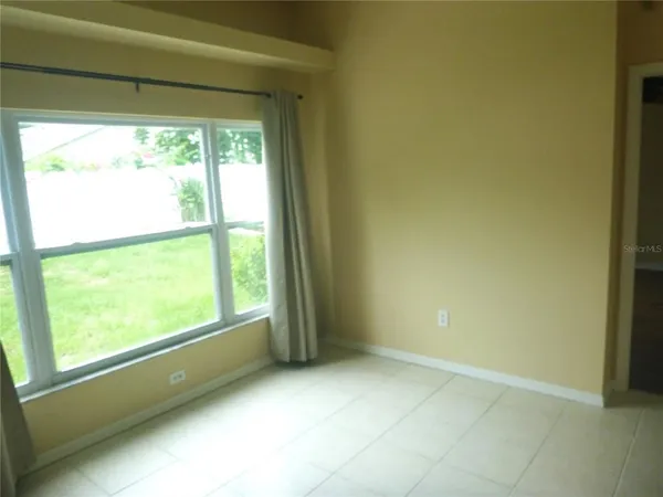 a view of an empty room with window and refrigerator