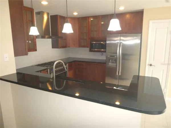 a kitchen with stainless steel appliances granite countertop a refrigerator and a stove