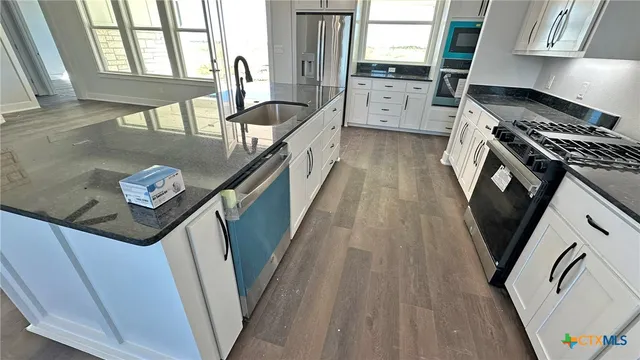 a kitchen with stainless steel appliances granite countertop a sink a stove and a refrigerator