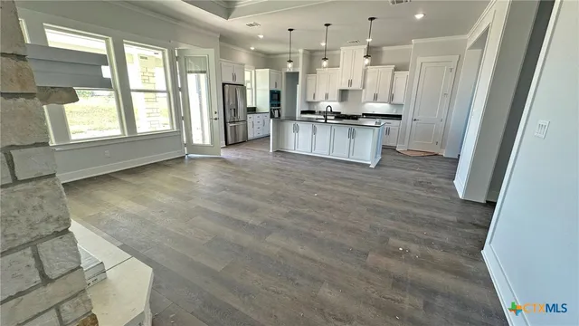 an empty room with wooden floor chandelier and windows